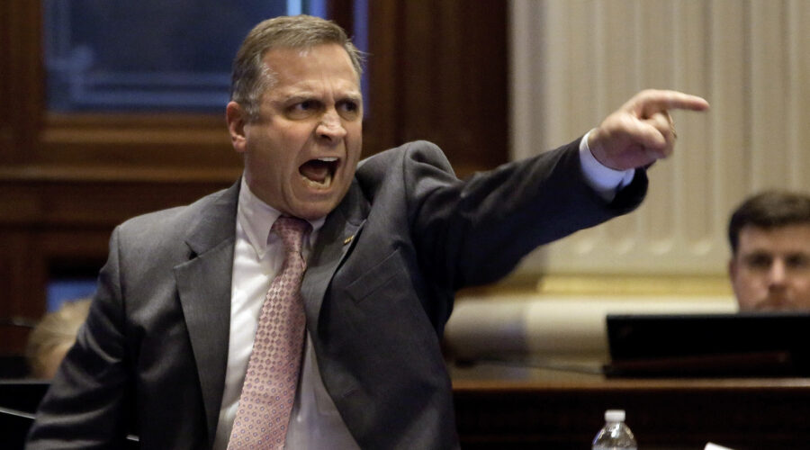 A furious man in a suit, pointing and shouting.