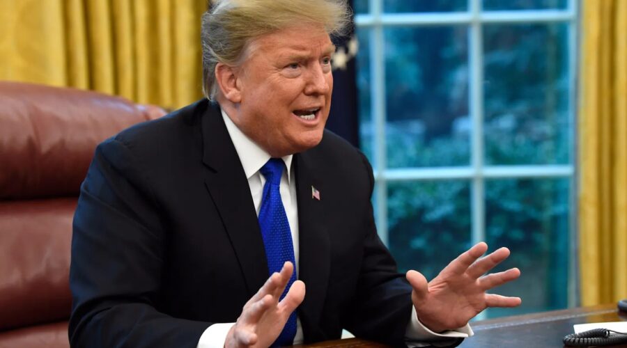 Trump sitting at the Resolute desk, hands spread, mouth open, clearly angry.